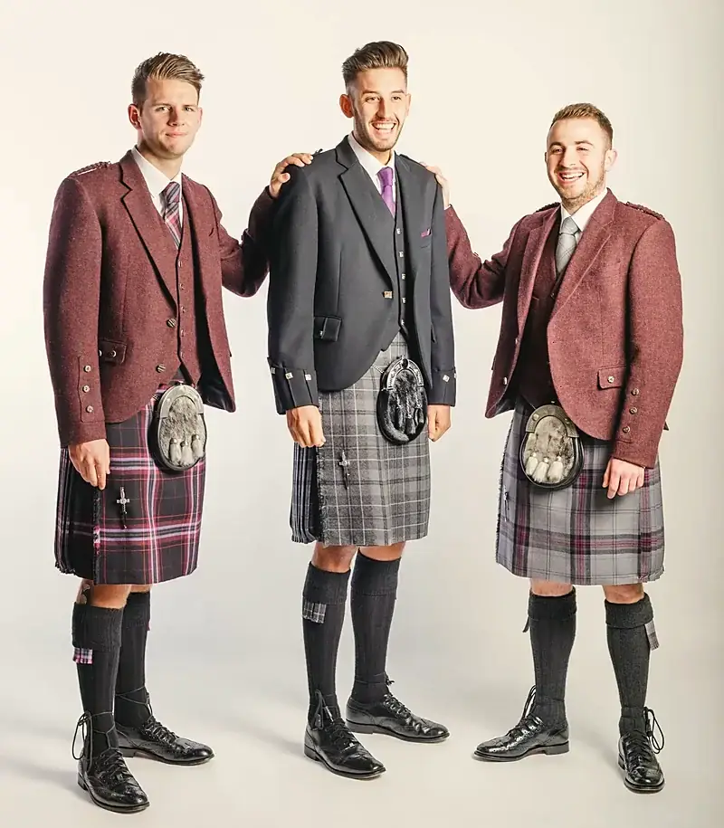 Three men in burgundy tweed jackets and tartan kilts